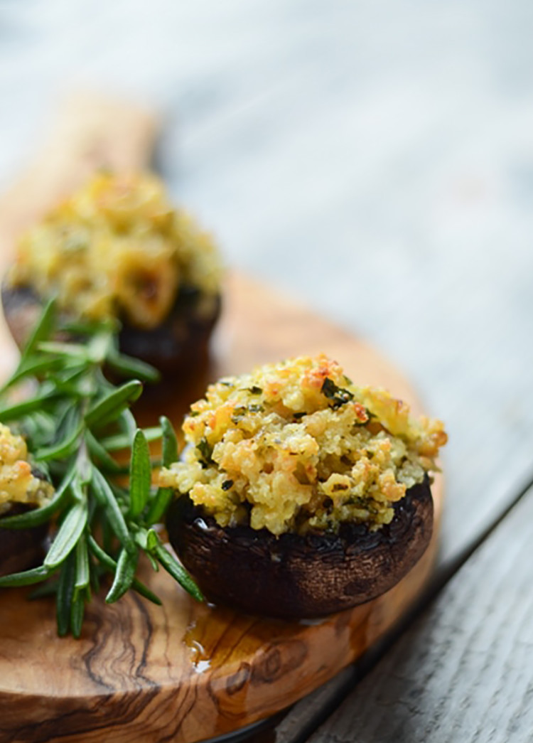 shrimp stuffed mushrooms on a wooden board with fresh rosemary sprigs