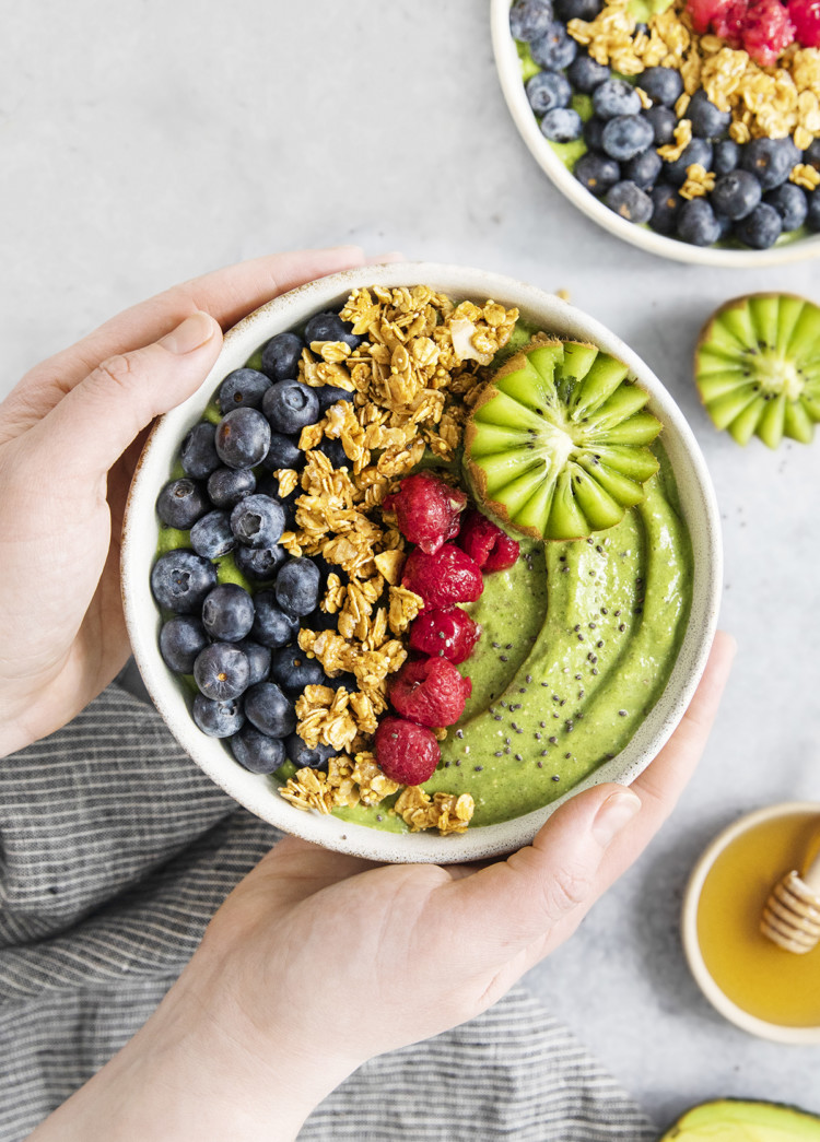woman holding a green smoothie bowl
