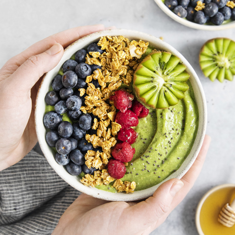 woman holding a green smoothie bowl