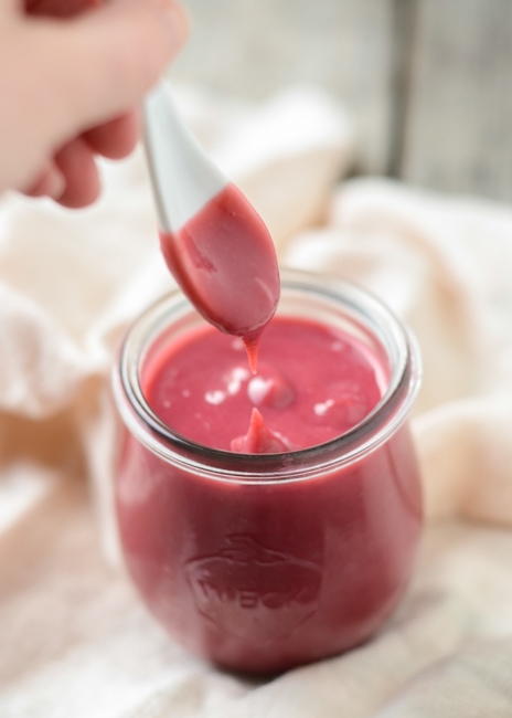 a jar of raspberry curd with a white spoon