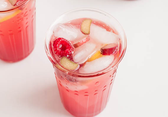 rhubarb lemonade in a glass with raspberries and rhubarb slices