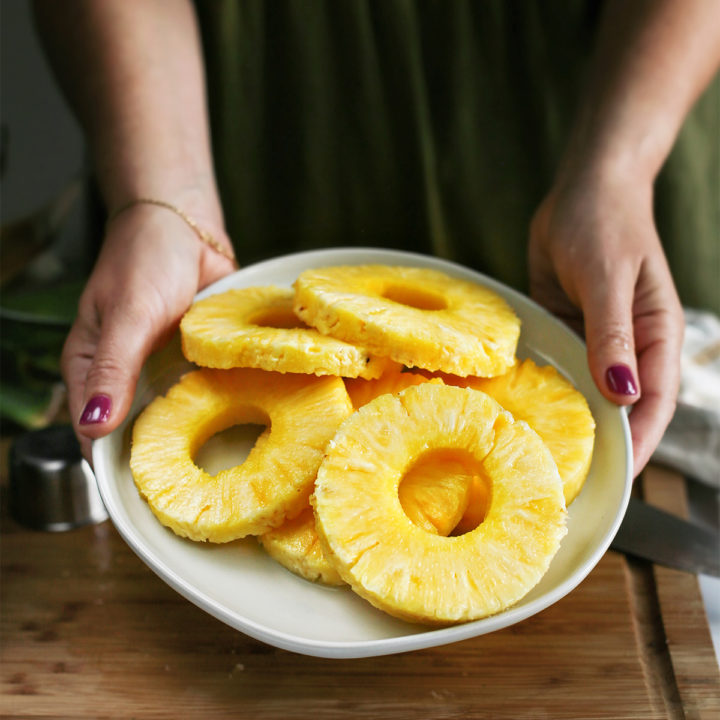 woman showing how to cut a pineapple in rings