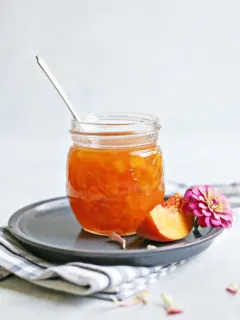 peach syrup in a jar with a spoon