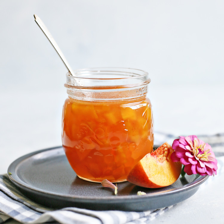 peach syrup in a jar with a spoon