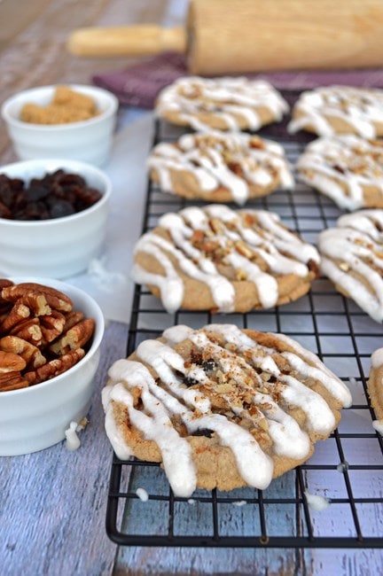 Close up of cinnamon bun cookies on a wire rack, next to bowls with filling options. 