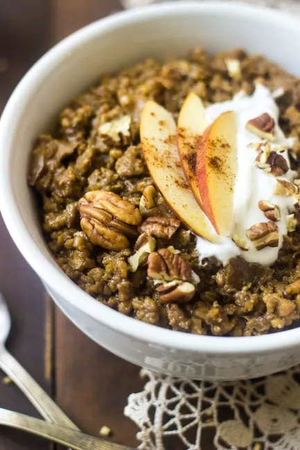 bowl of slow cooker oatmeal topped with nuts and apple slices