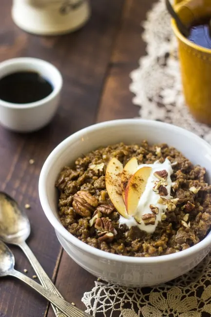 bowl of slow cooker oatmeal topped with nuts and apple slices
