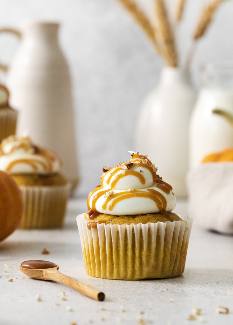close up photo of a pumpkin cupcake with cream cheese frosting