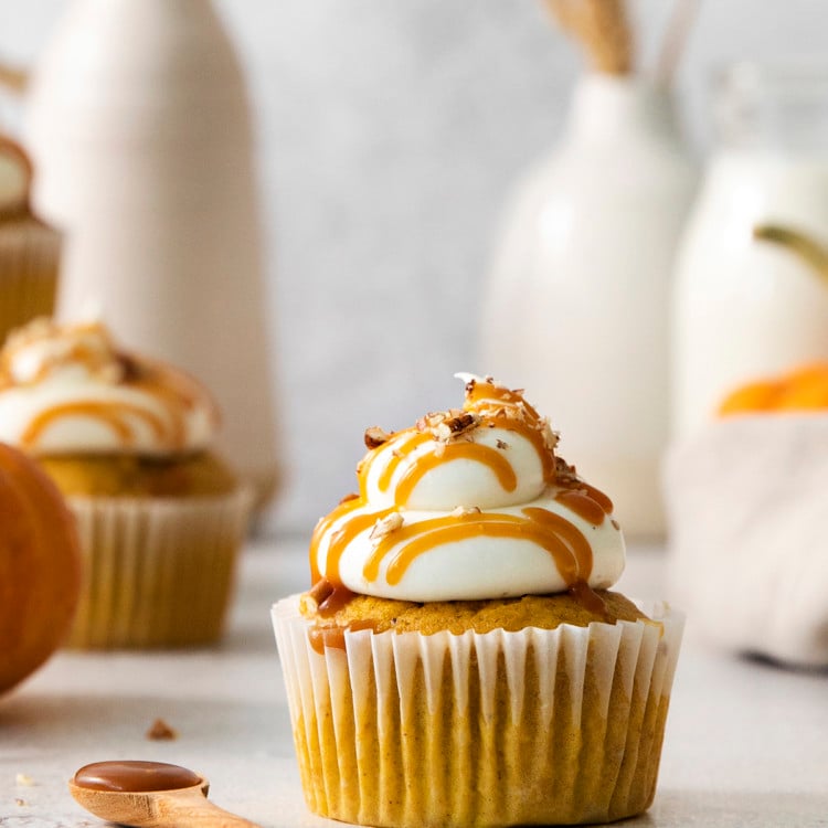 close up photo of a pumpkin cupcake with cream cheese frosting