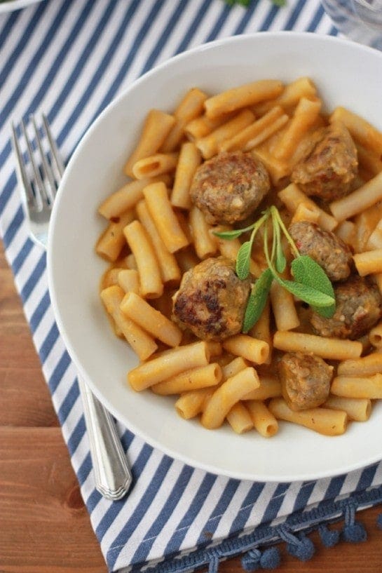 photo of Butternut Squash Sauce with Sausage Meatballs in a white bowl with a striped tea towel and fork