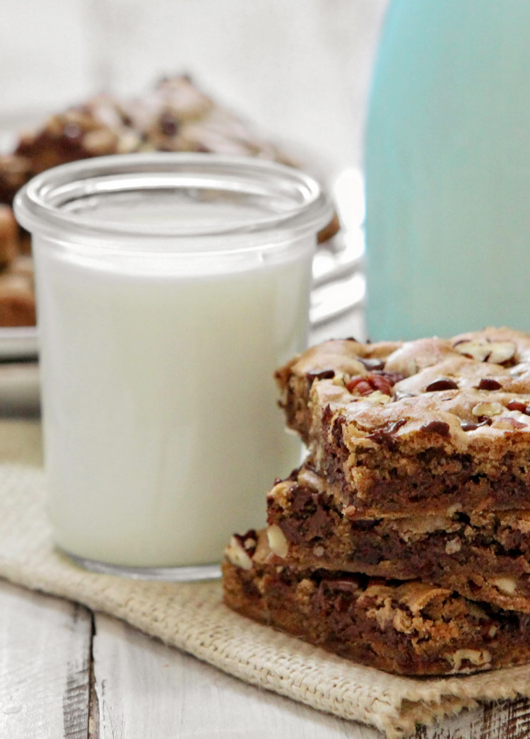 a stack of chocolate chip blondies next to a glass of milk