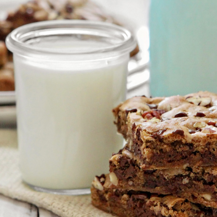 a stack of chocolate chip blondies next to a glass of milk