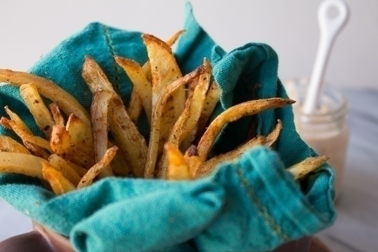 seasoned fries in blue towel with dipping sauce in backrgound