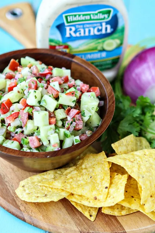 Creamy Cucumber Salsa in bowl on platter with chips, ranch dressing and cilantro