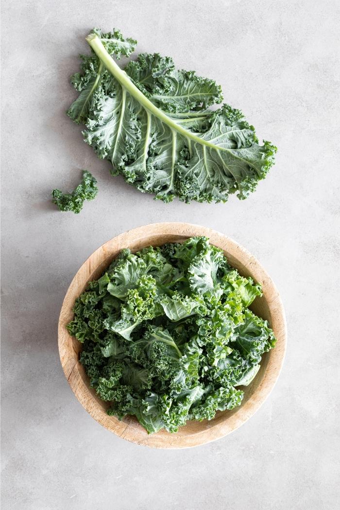 overhead shot of kale leaves in a wooden bowl