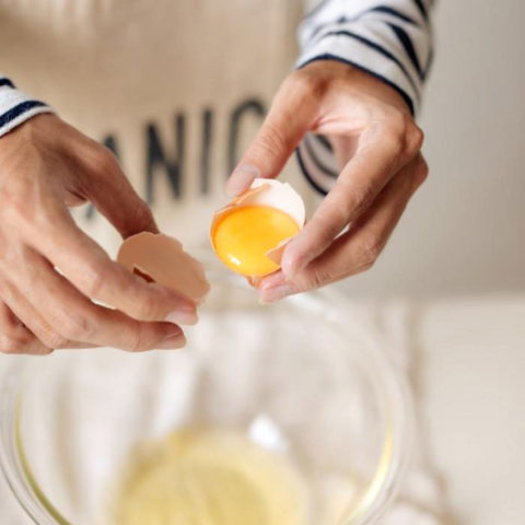 hands holding cracked egg and separating yolk from white