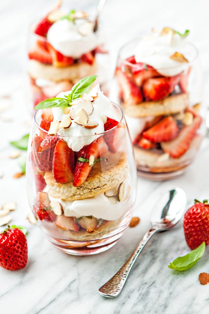 Basil Balsamic Strawberry Shortcake Parfaits in glasses on a white marble counter
