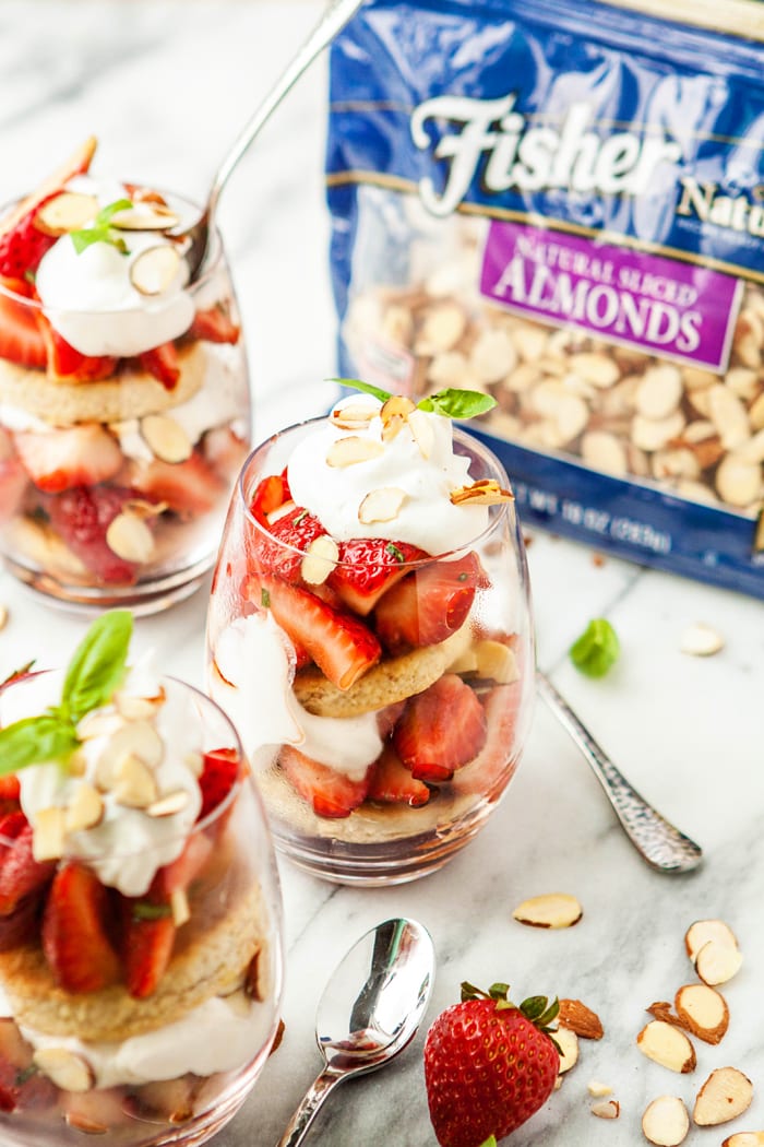 Basil Balsamic Strawberry Shortcake Parfaits in glasses on a white marble counter with a bag of almonds