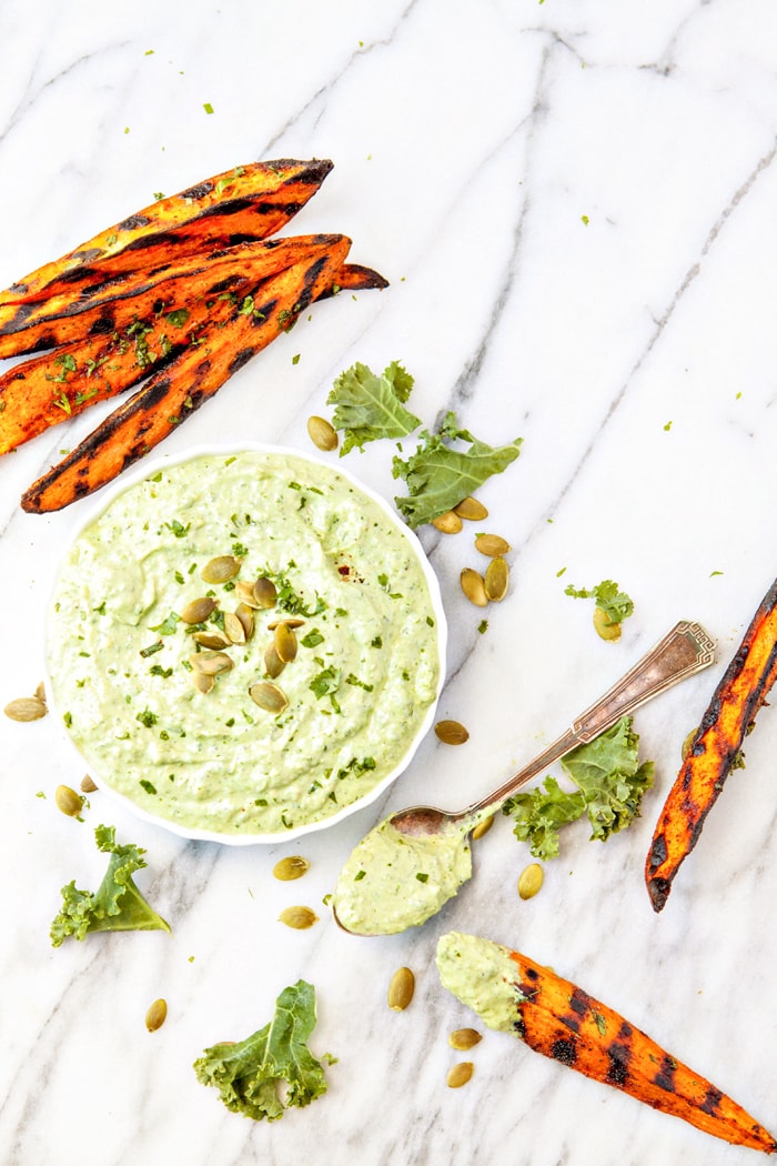 overhead photo of Pesto Dipping sauce in a white bowl on a marble counter with grilled sweet potatoes