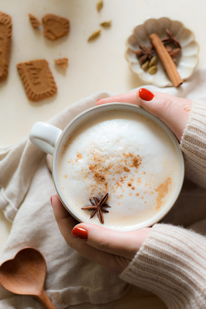 A woman's hand wrapped around a pumpkin chai latte 