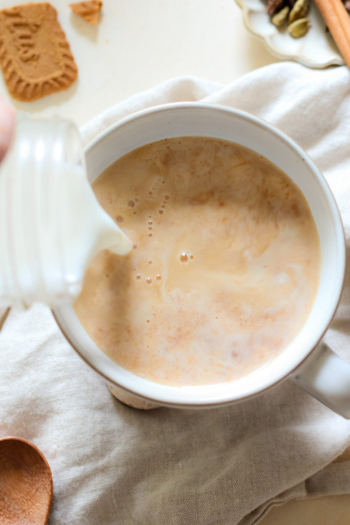 Milk being poured into a pumpkin spice chai tea latte