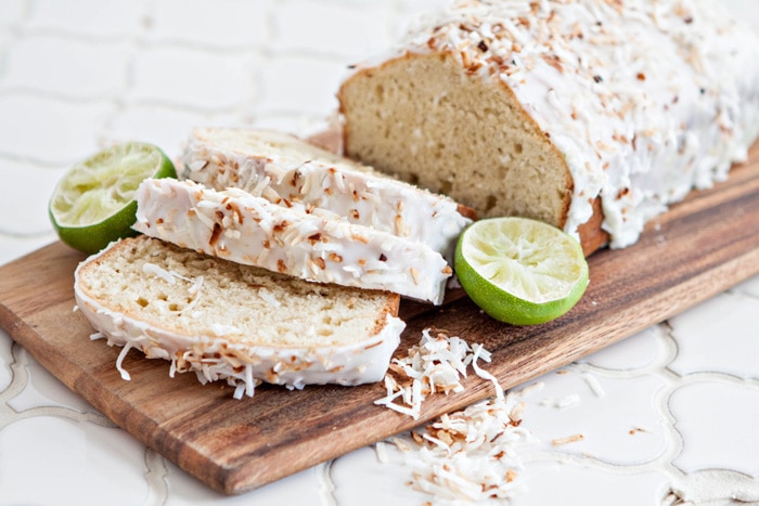 a photo of coconut banana bread with lime glaze and toasted coconut sliced on a cutting board