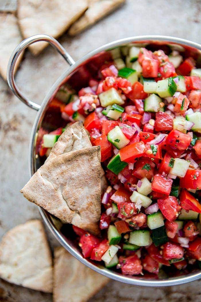 Greek Pico de Gallo with Cucumber  in a metal bowl surrounded by homemade pita chips for an easy summer appetizer