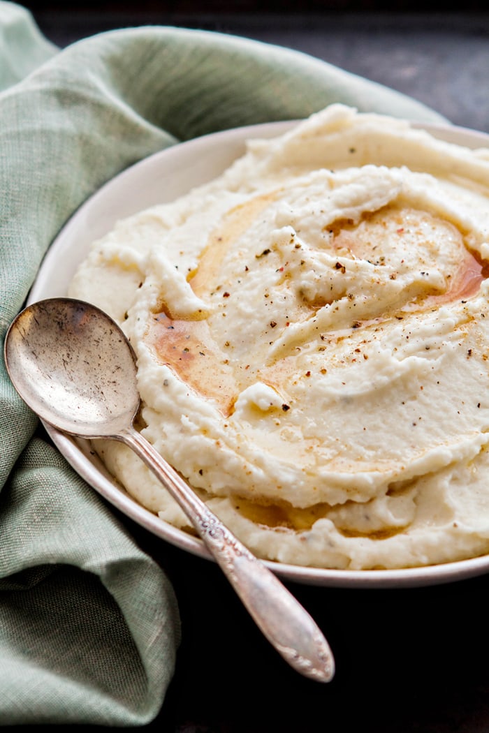 parmesan mashed potatoes with browned butter in a serving bowl with a serving spoon on a holiday table