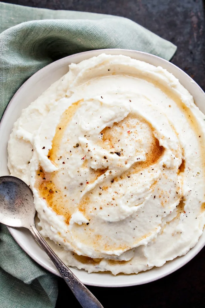 overhead photo of a bowl of parmesan mashed potatoes with browned butter with a serving spoon