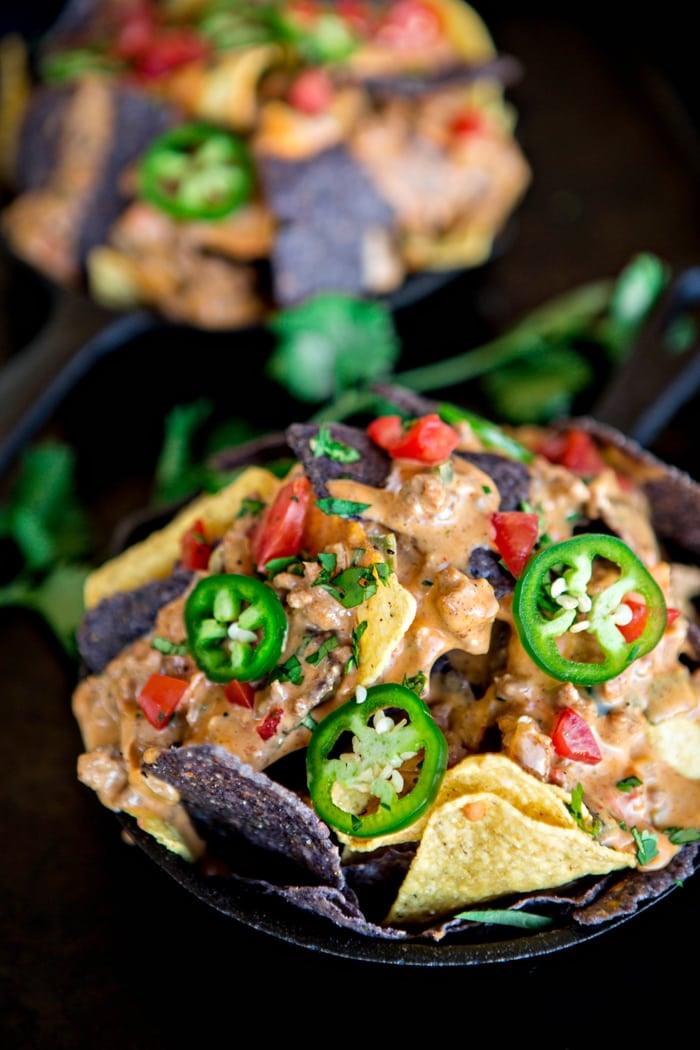 crock pot queso dip atop tortilla chips with a jalapeno garnish