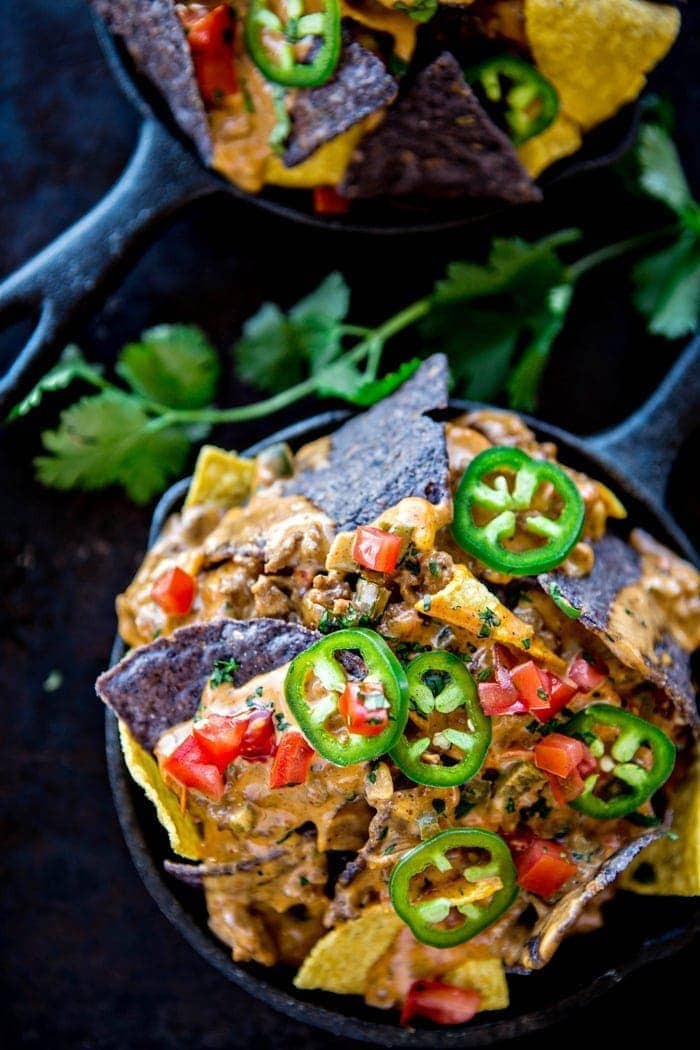 bowl of tortilla chips topped with crock pot queso dip and garnishes