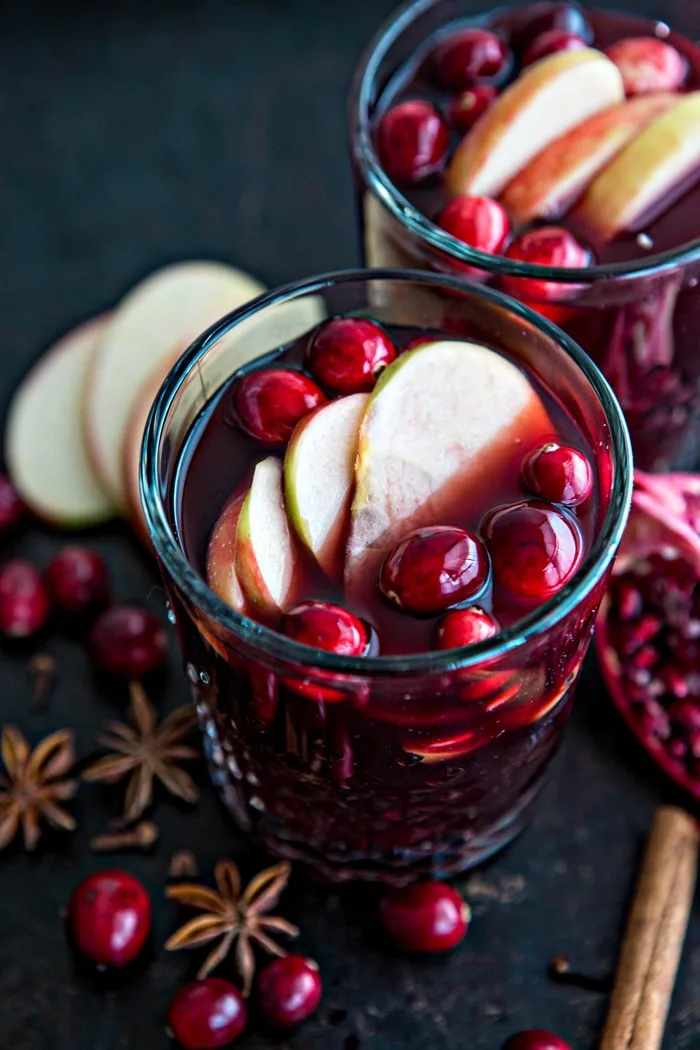 hot mulled wine garnished with apple slices and cranberries