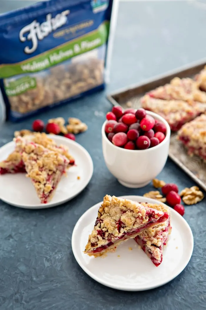 two plates of cranberry bars next to bowl of fresh cranberries