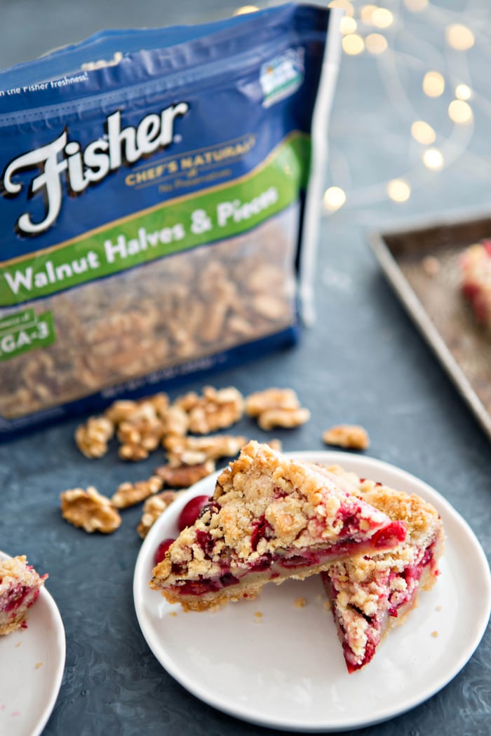 cranberry bars on white plate next to bag of walnuts