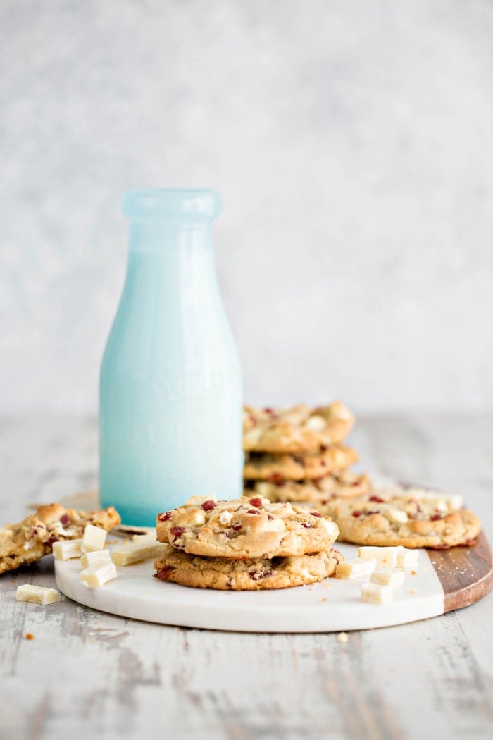 copycat subway raspberry cheesecake cookies on a marble and wood board with a glass milk bottle