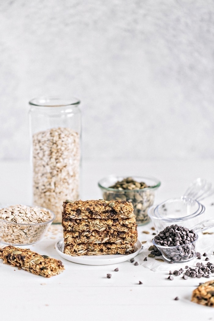 photo of pumpkin chocolate chip chai granola bars, a healthy granola bar recipe, on a light background surrounded by the recipe ingredients