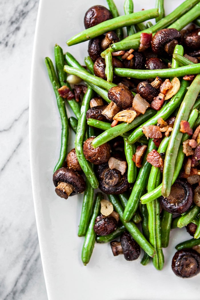 sauteed greens beans and mushrooms on white serving platter