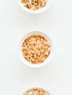 3 white bowls of toasted coconut on white background