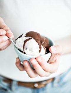 girl holding a bowl of ice cream with chocolate topping