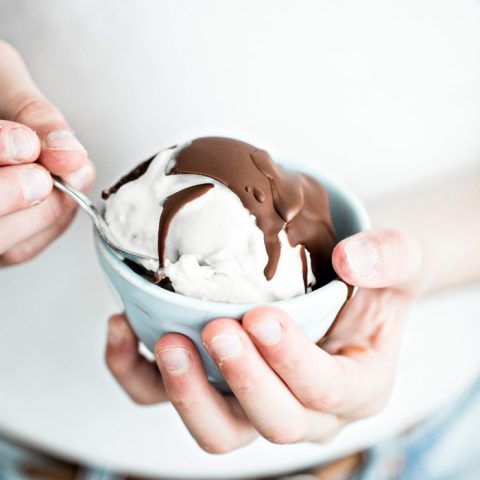 girl holding a bowl of ice cream with chocolate topping