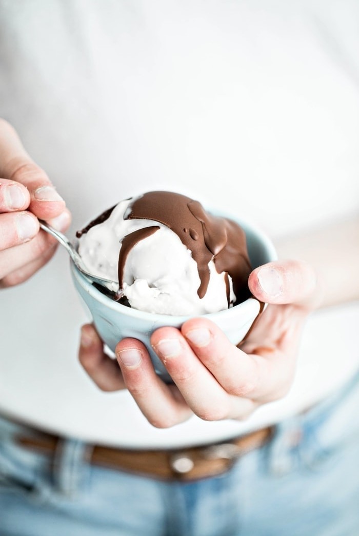 girl holding a bowl of ice cream with chocolate topping