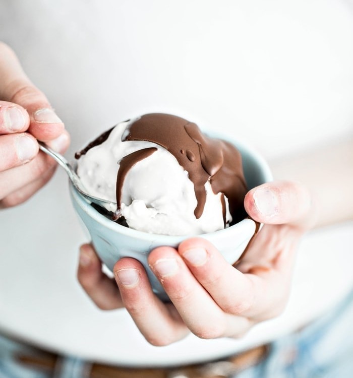 girl holding a bowl of ice cream with chocolate topping