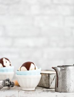 two bowls of vanilla ice cream with chocolate topping in front of a grey brick wall