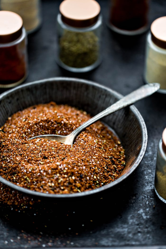 bowl of pork rub spice blend surrounded by spice jars