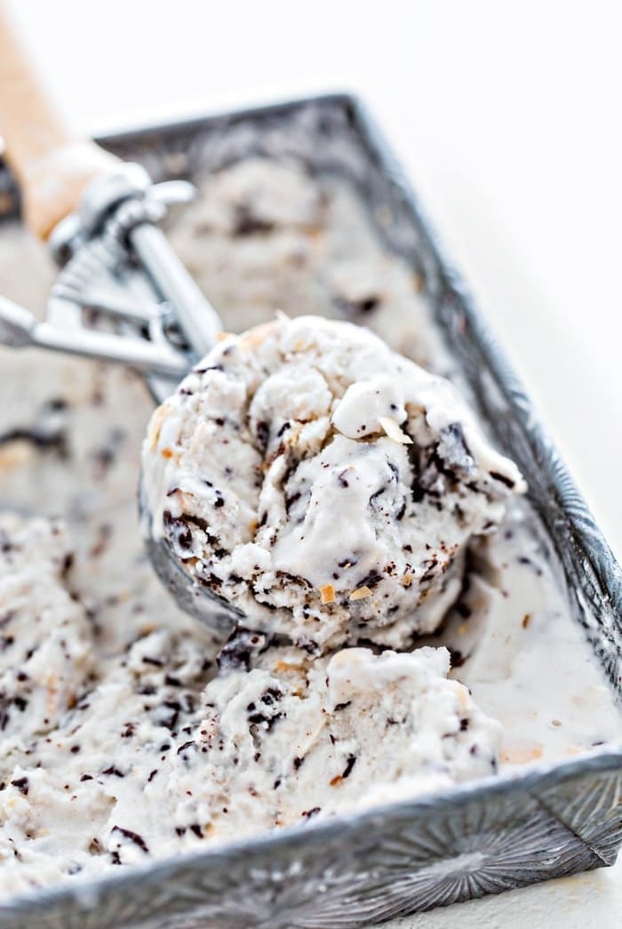 ice cream scoop in an ice cream container with ice cream on white background