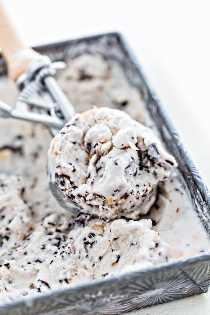 ice cream scoop in an ice cream container with ice cream on white background