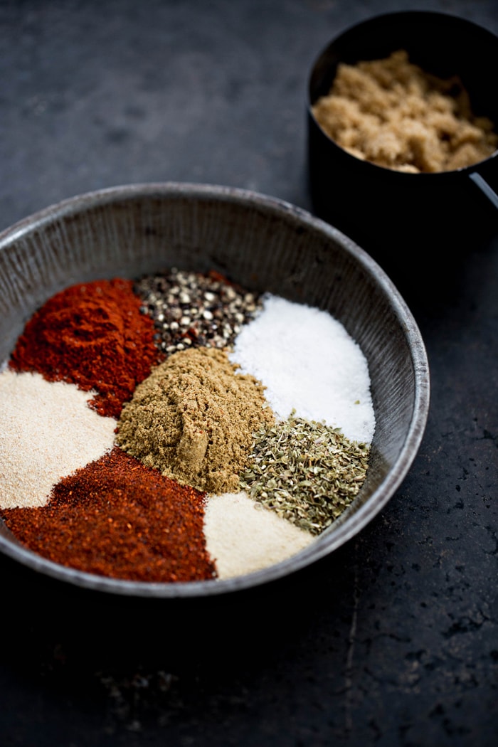 bowl of ingredients to make homemade pork rub on a dark background