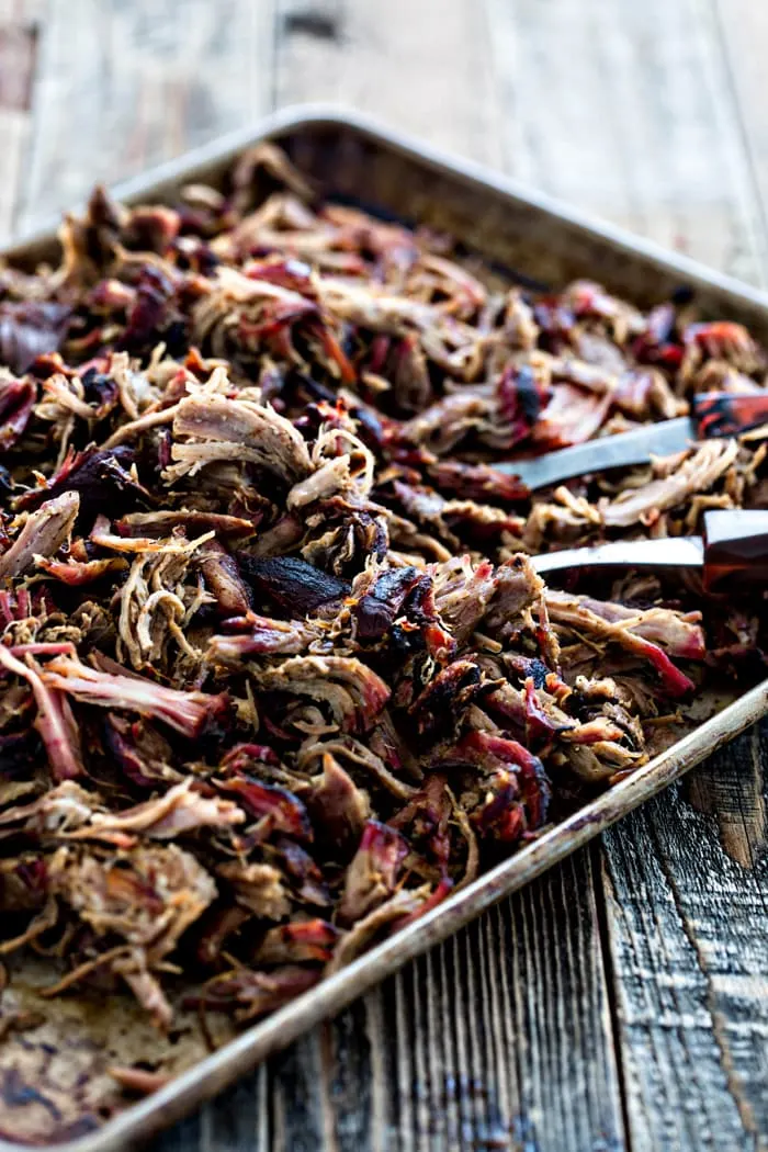 photo of a sheet pan with cooked pulled pork from this smoked pork butt recipe