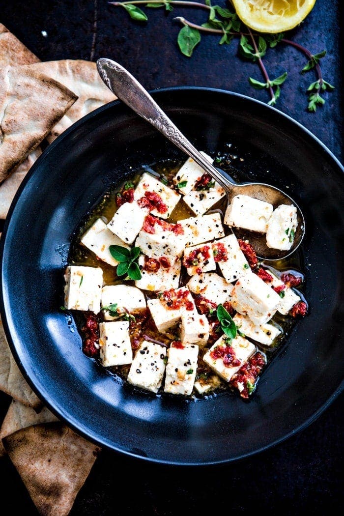 black bowl with marinated feta surrounded by pita chips