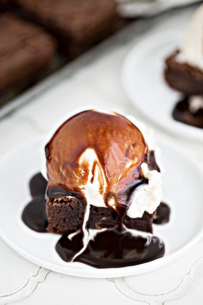 fudgy brownies on plate with ice cream and hot fudge